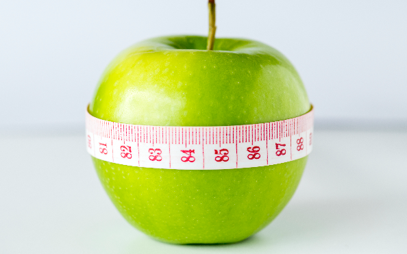 Zielone jabłko owinięte miarką centymetrową.